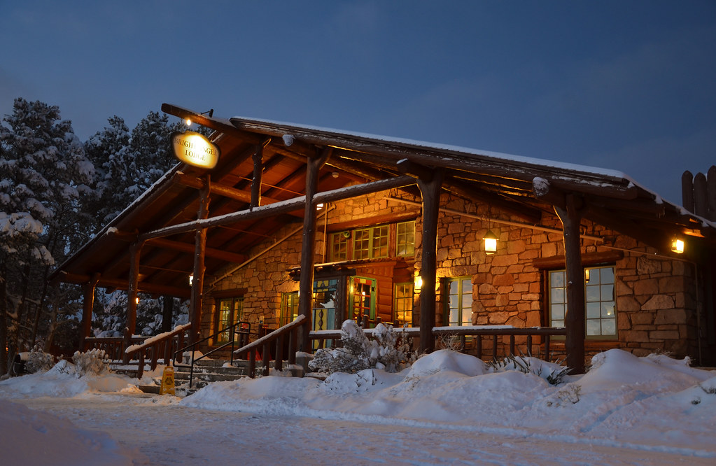 Timber lodge glowing at dusk surrounded by deep snow